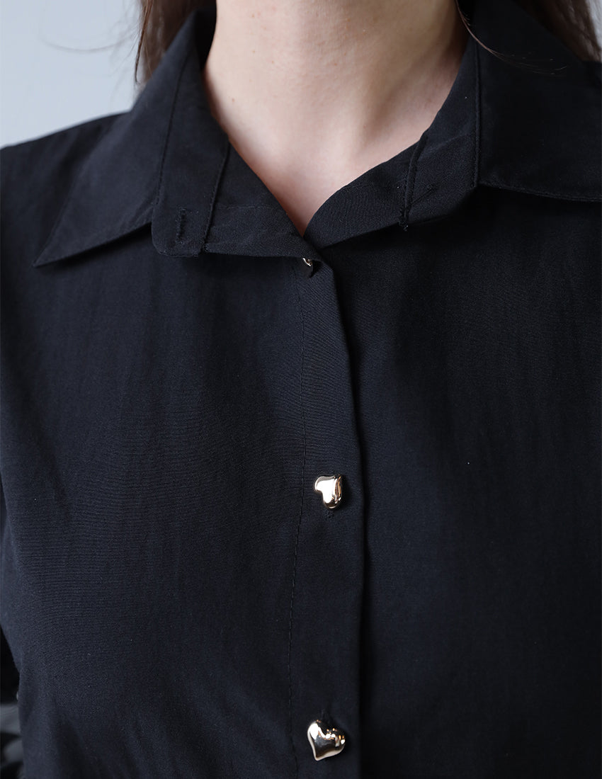 A black shirt with chiffon at the waist and golden heart-shaped buttons.