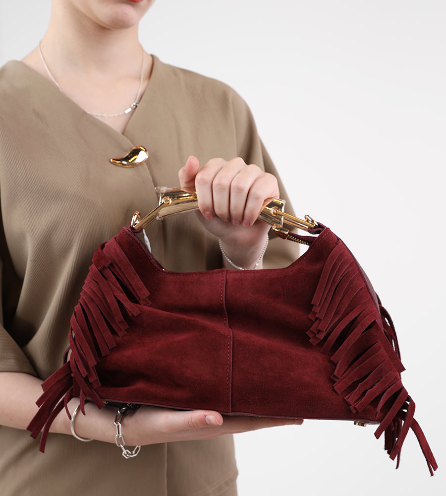 Suede bag with fringed edges and a gold handle