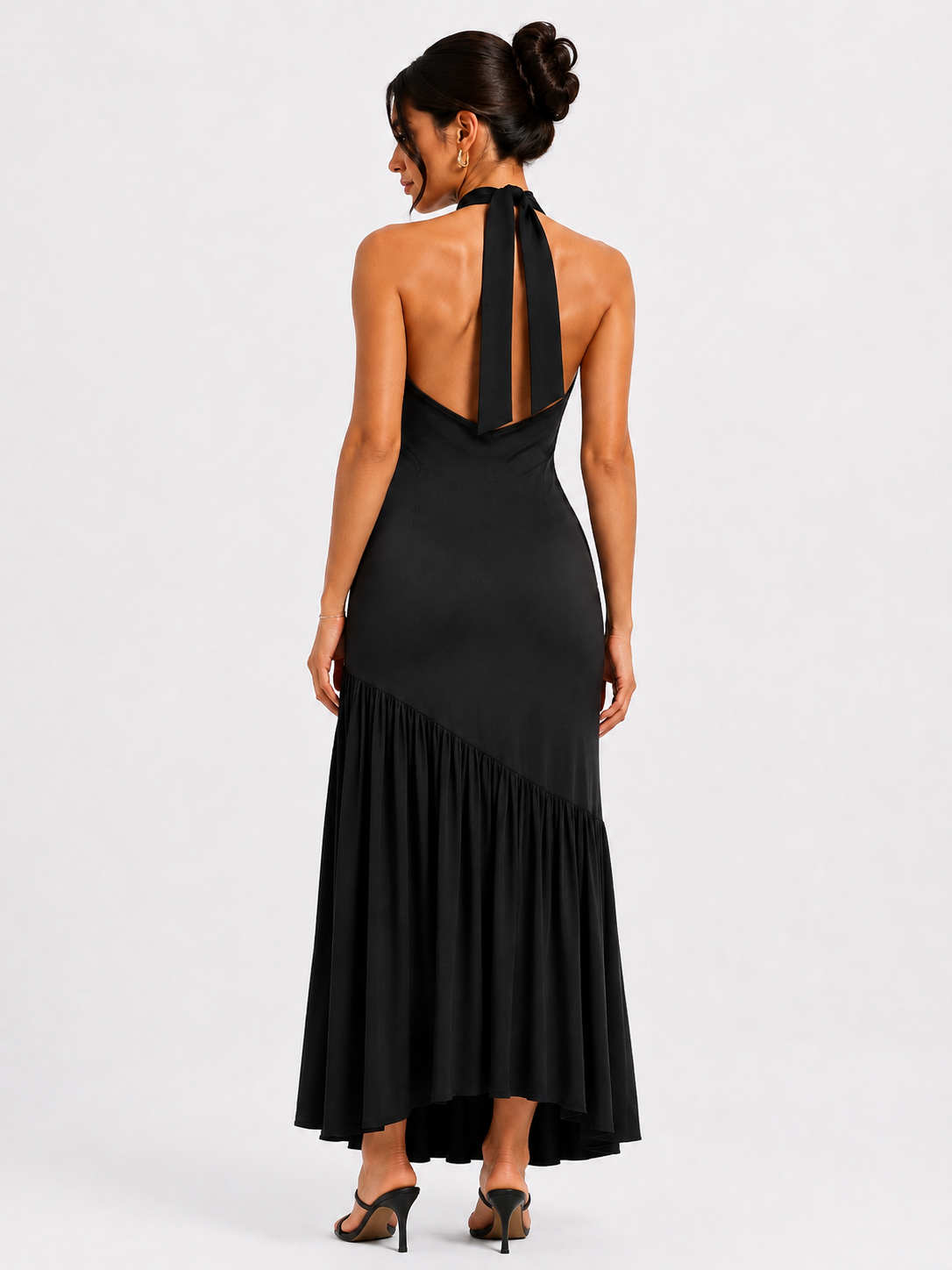 A long, backless dress featuring an asymmetrical waist, a front slit, and a neck tie.