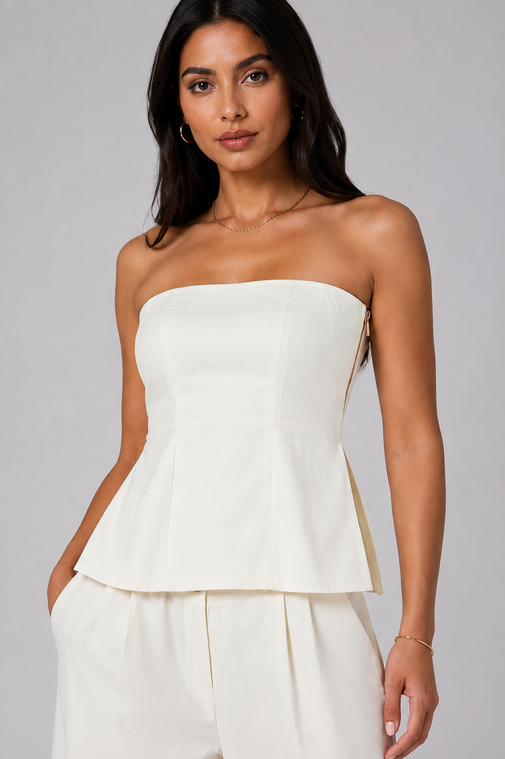 White set tube top with a gold zipper and wide-leg trousers.