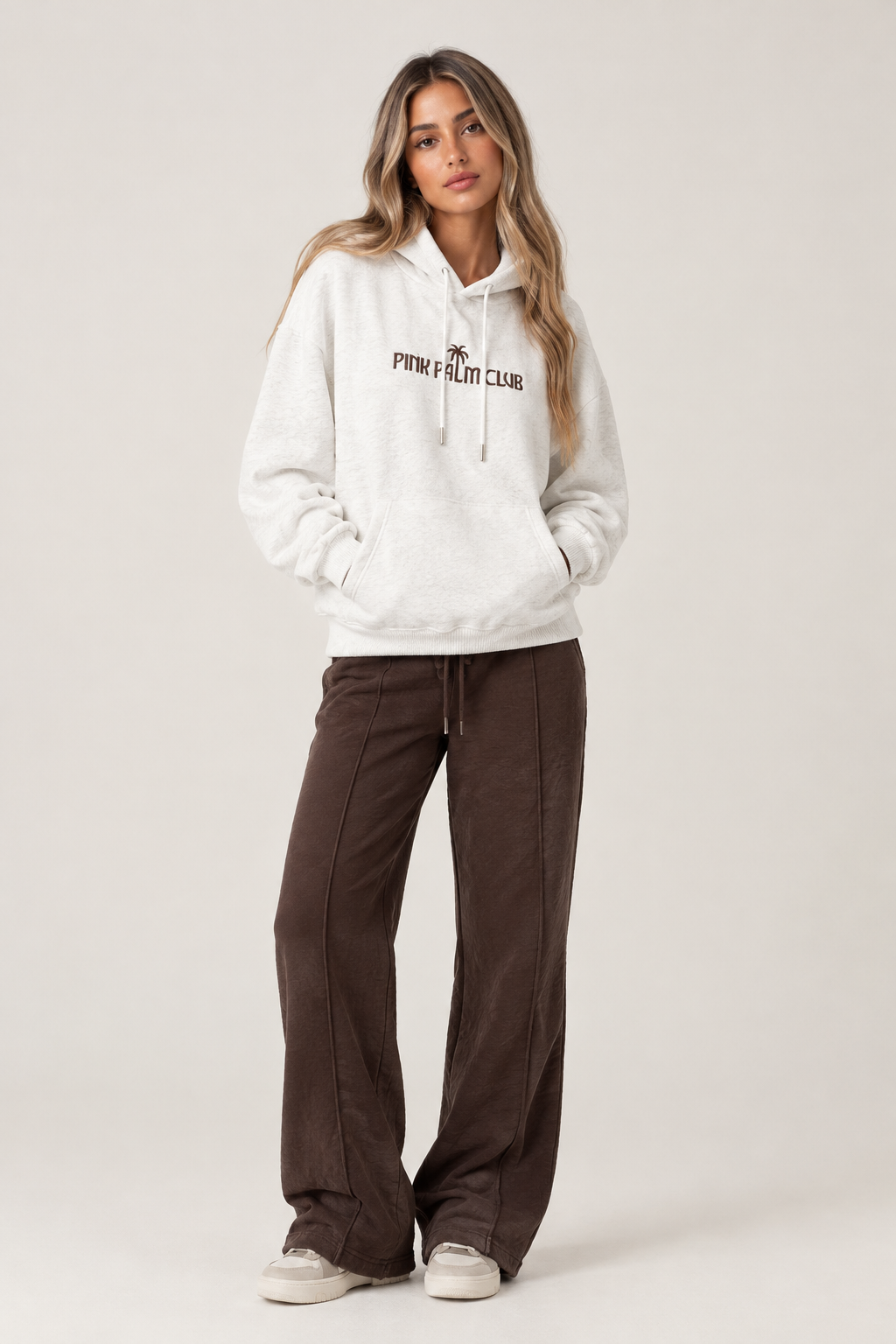 White oversized hoodie with a brown boat design on the back and writing on the front.