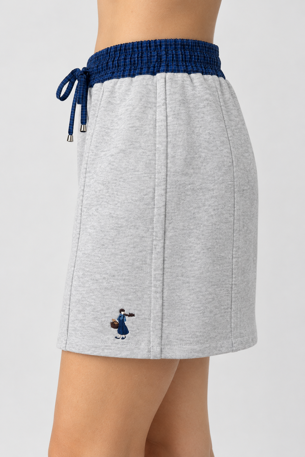 Light gray mini skirt with a drawing of a little girl, elastic waistband, navy blue plaid pattern.