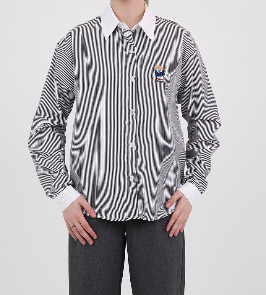 A striped white collared shirt with a teddy bear on the front