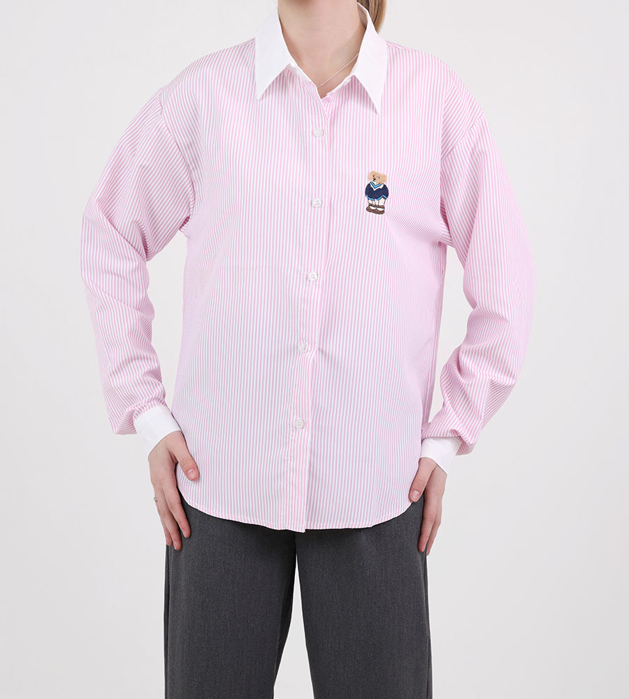A striped white collared shirt with a teddy bear on the front