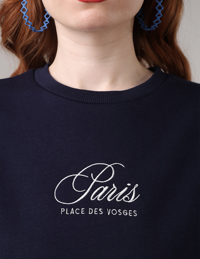 Navy blue blouse with the word "Paris" printed on it, worn with a shirt underneath.