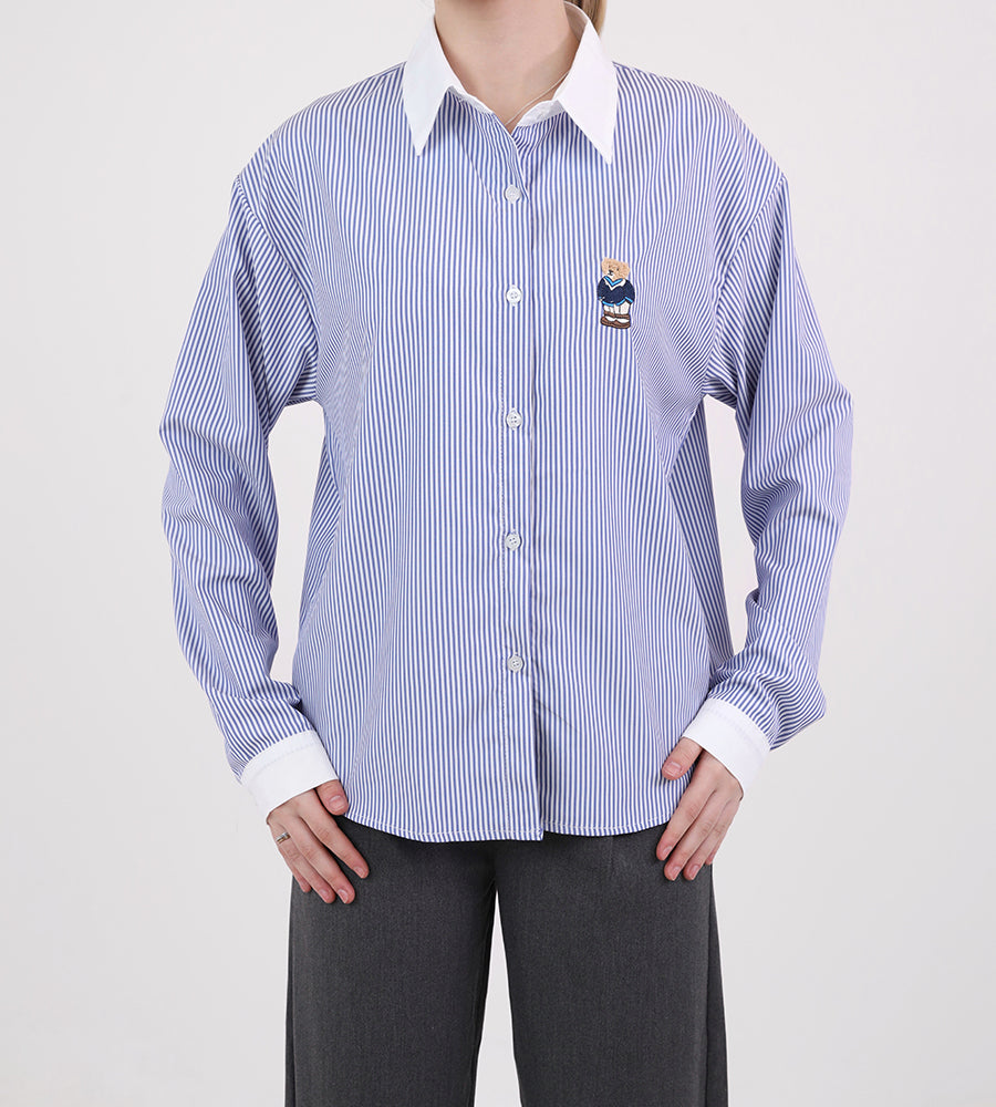 A striped white collared shirt with a teddy bear on the front
