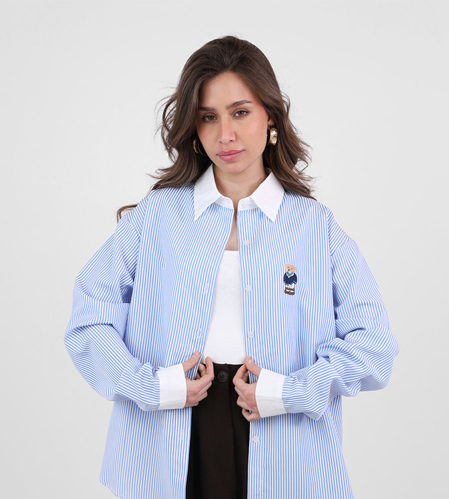 A striped white collared shirt with a teddy bear on the front