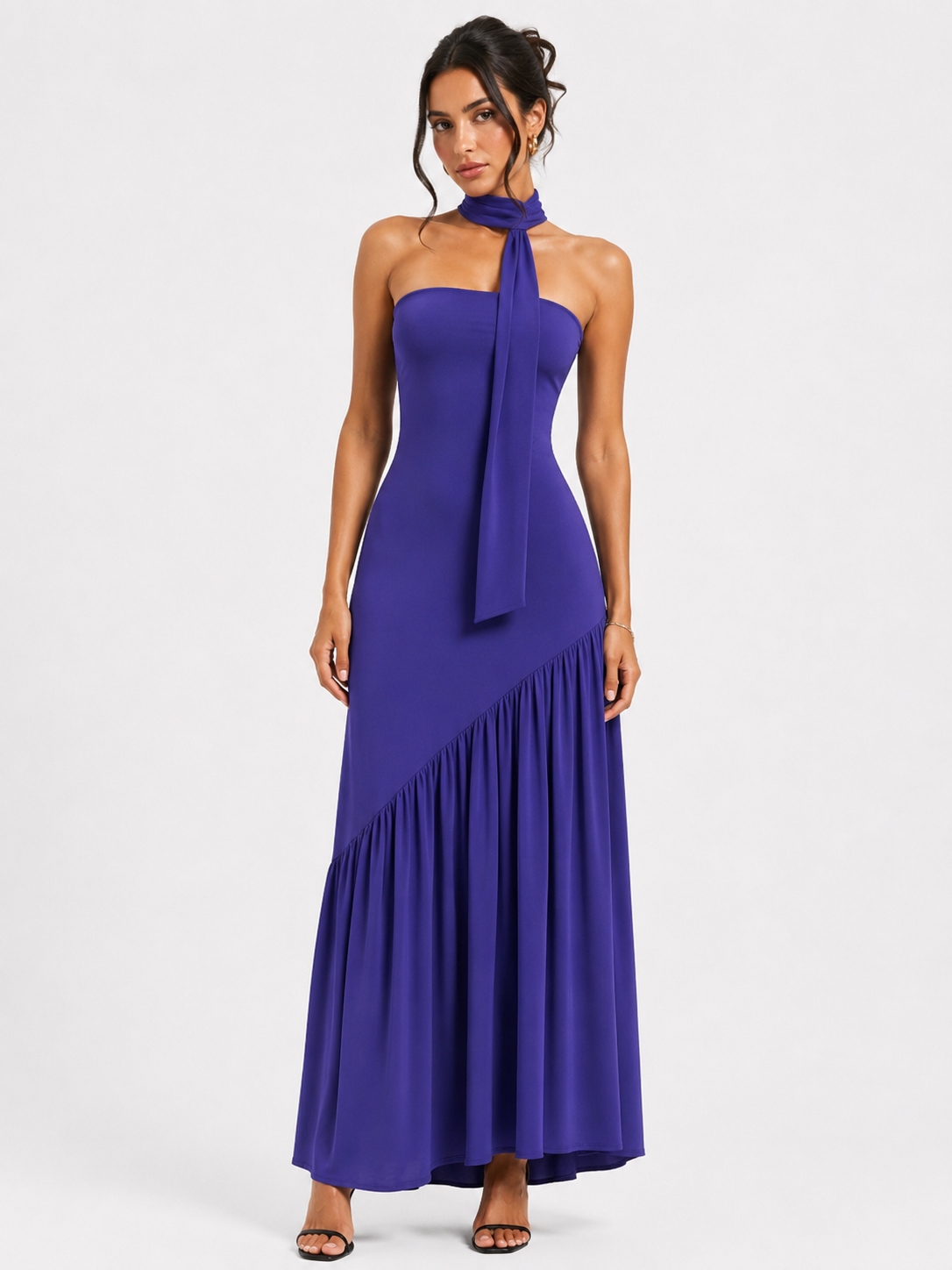 A long, backless dress featuring an asymmetrical waist, a front slit, and a neck tie.