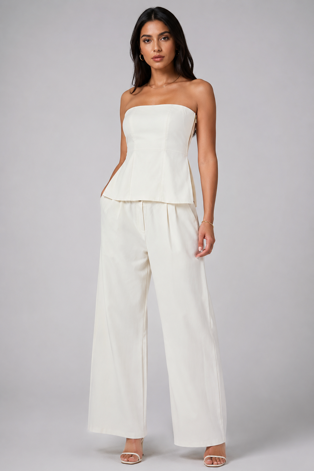 White set tube top with a gold zipper and wide-leg trousers.