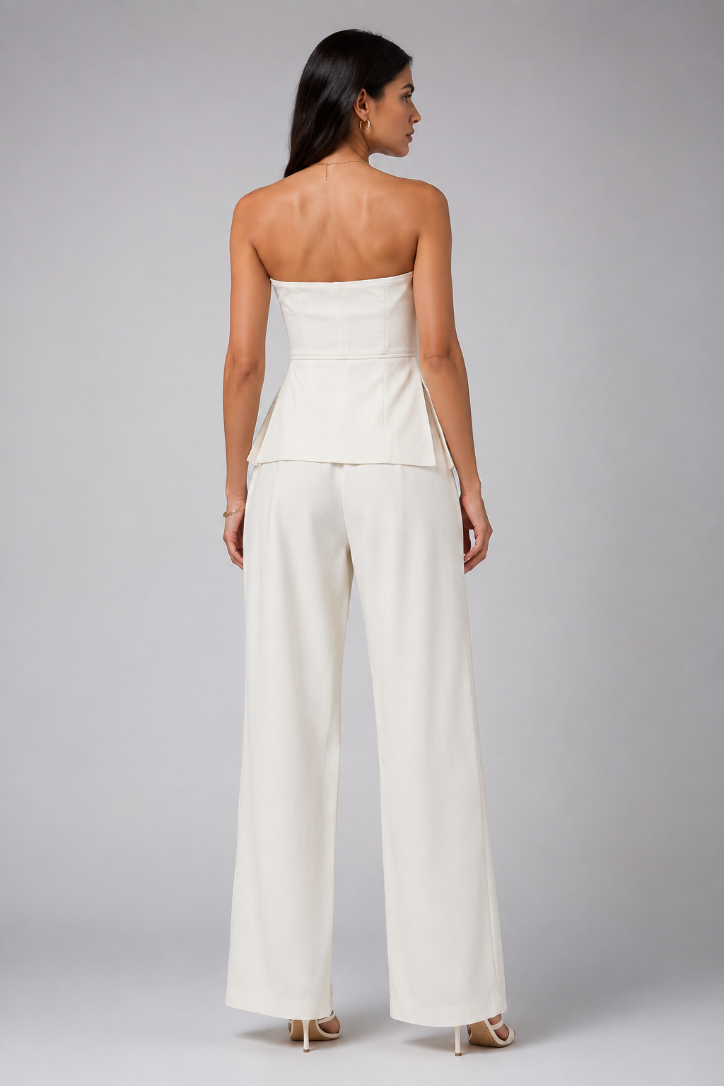 White set tube top with a gold zipper and wide-leg trousers.