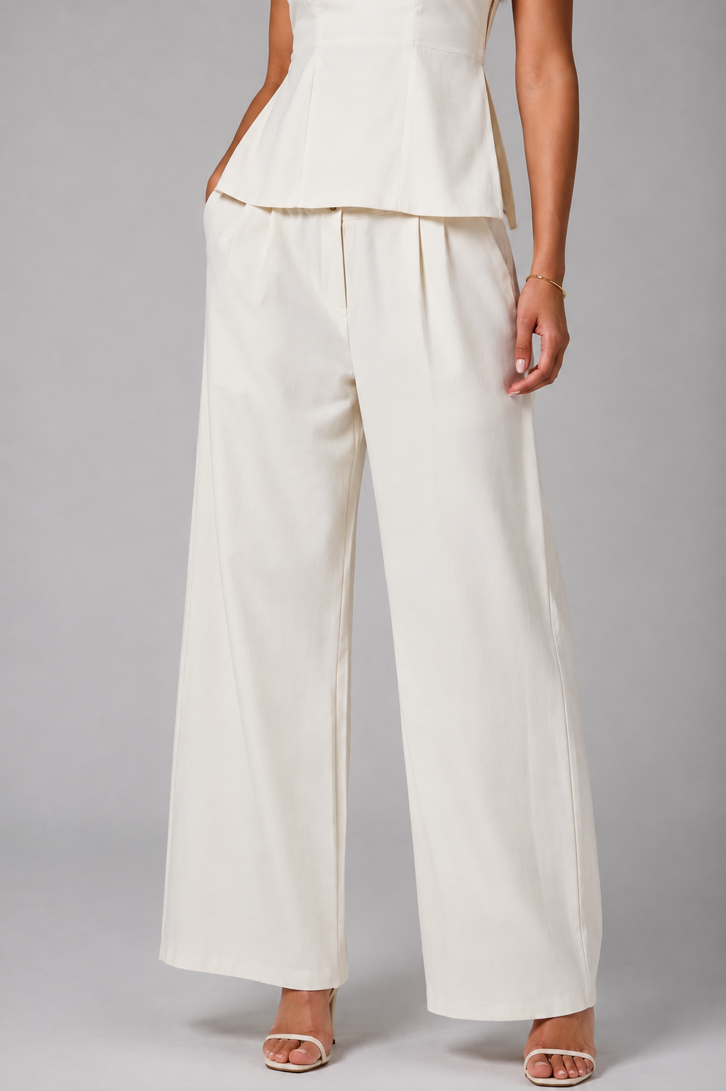 White set tube top with a gold zipper and wide-leg trousers.