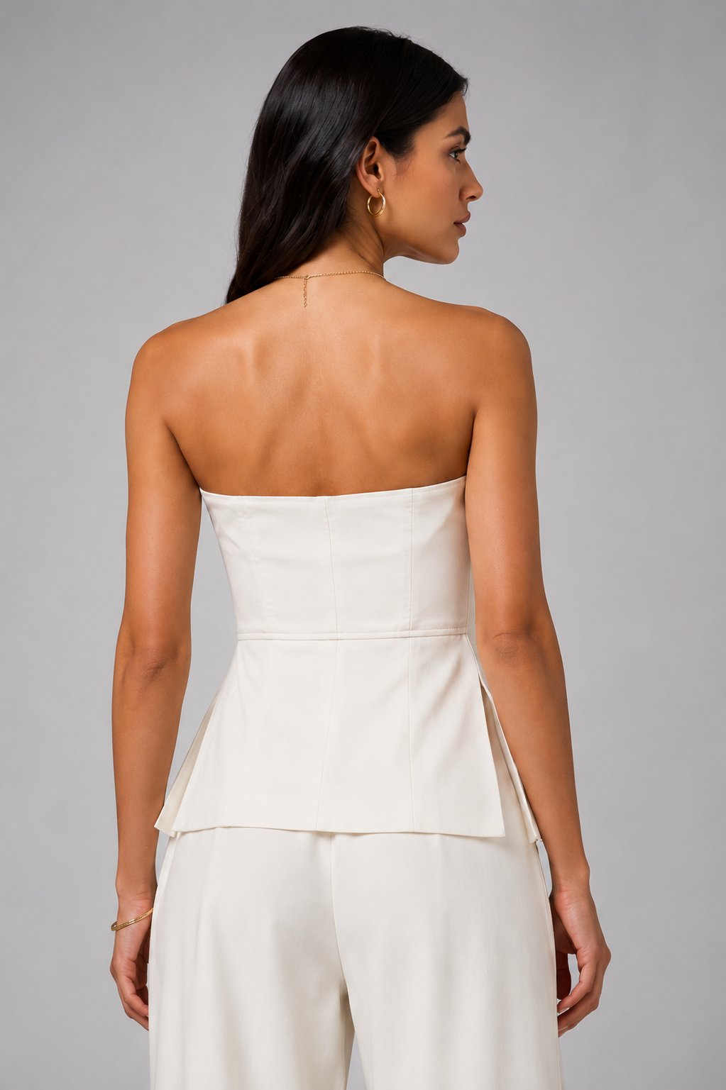 White set tube top with a gold zipper and wide-leg trousers.