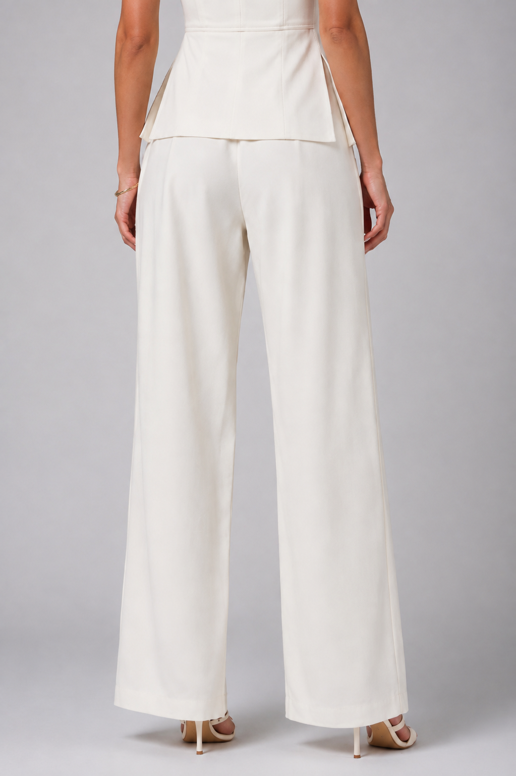 White set tube top with a gold zipper and wide-leg trousers.