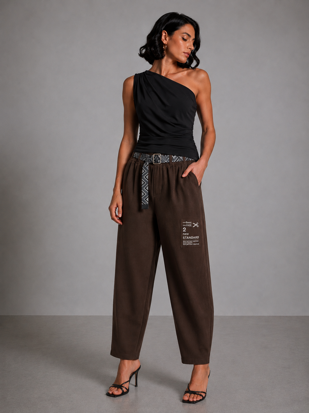 Brown trousers with gathered cuffs, a belt, and a side patch.