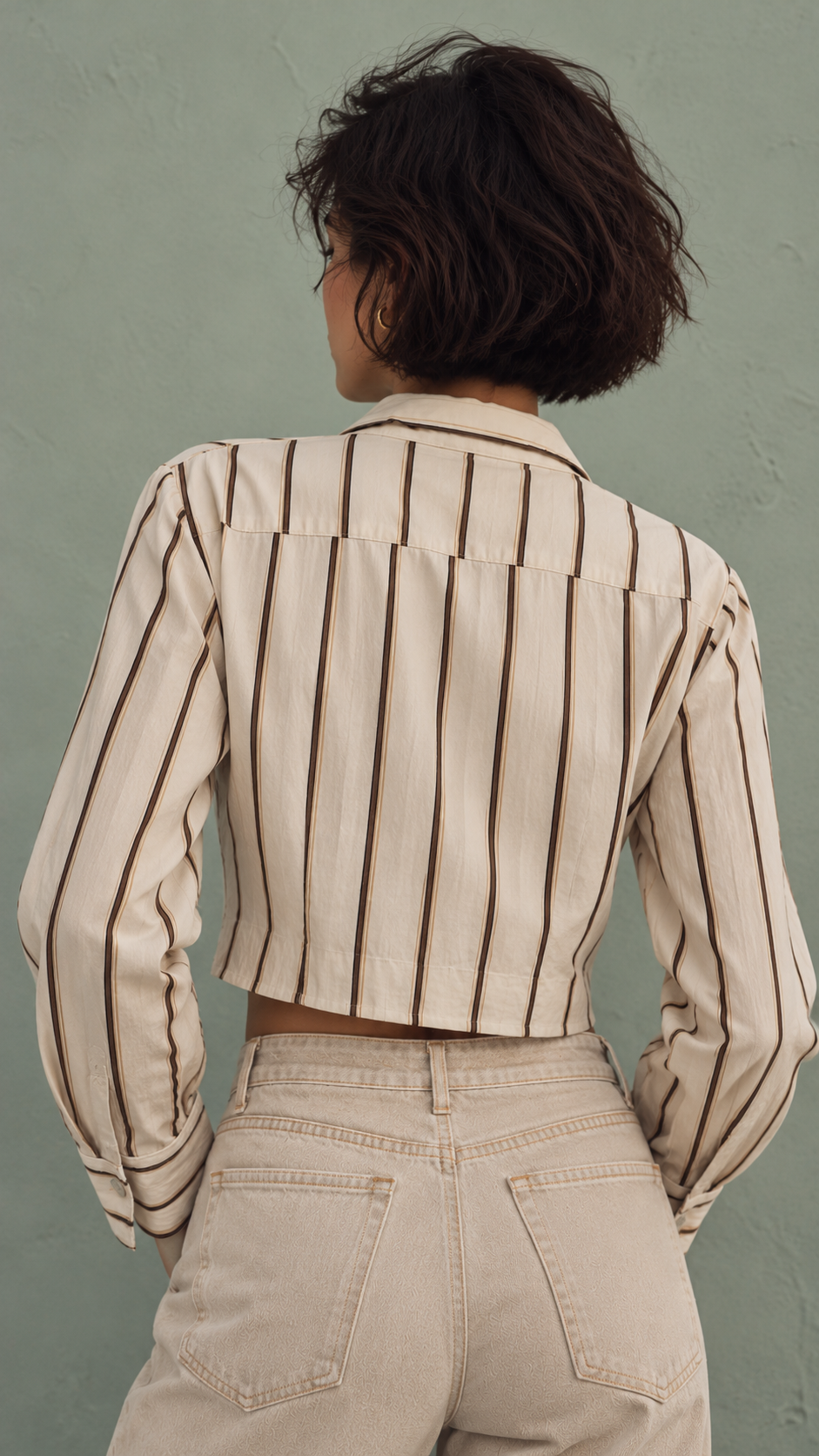 Beige striped cropped shirt with an open neckline, paired with a tank top and gold chain.