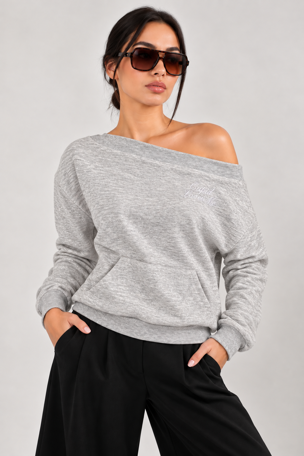 Off-shoulder gray shiny blouse with rhinestone wings on the back, writing on the chest, and a front pocket.
