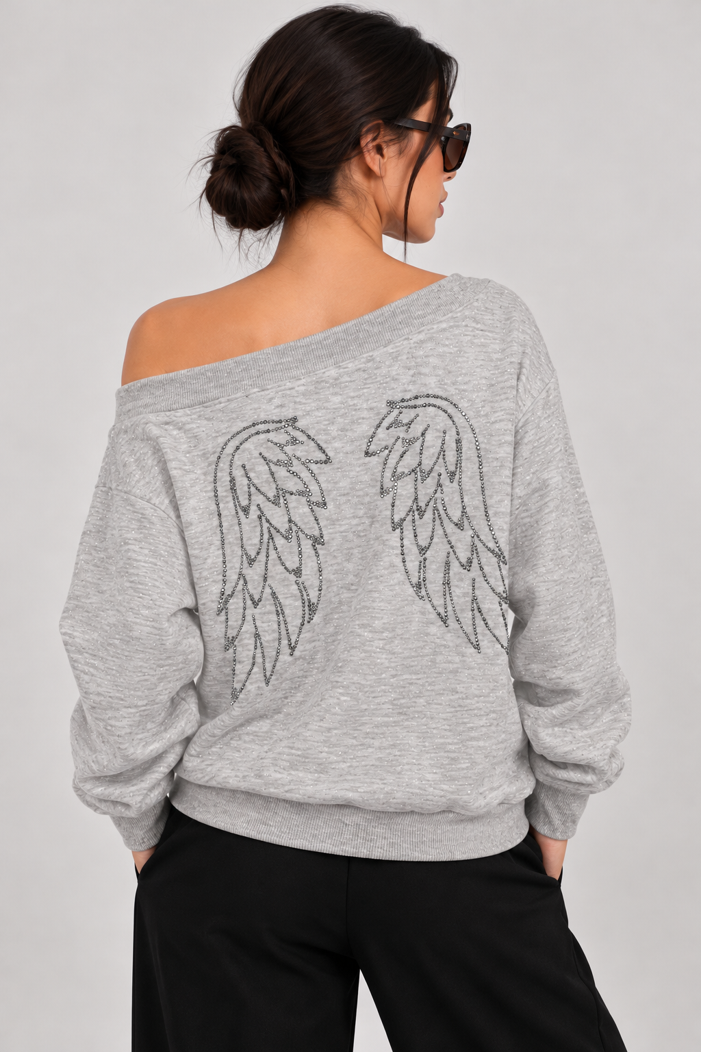 Off-shoulder gray shiny blouse with rhinestone wings on the back, writing on the chest, and a front pocket.