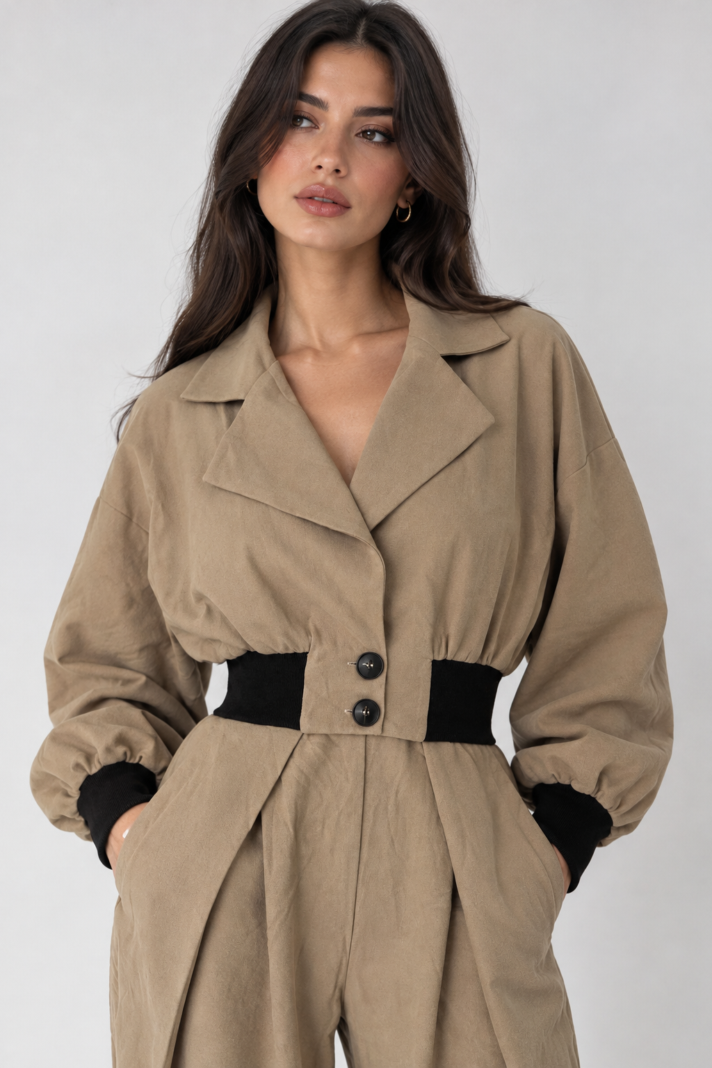 Beige short jacket with a brown elastic waist and button placket.