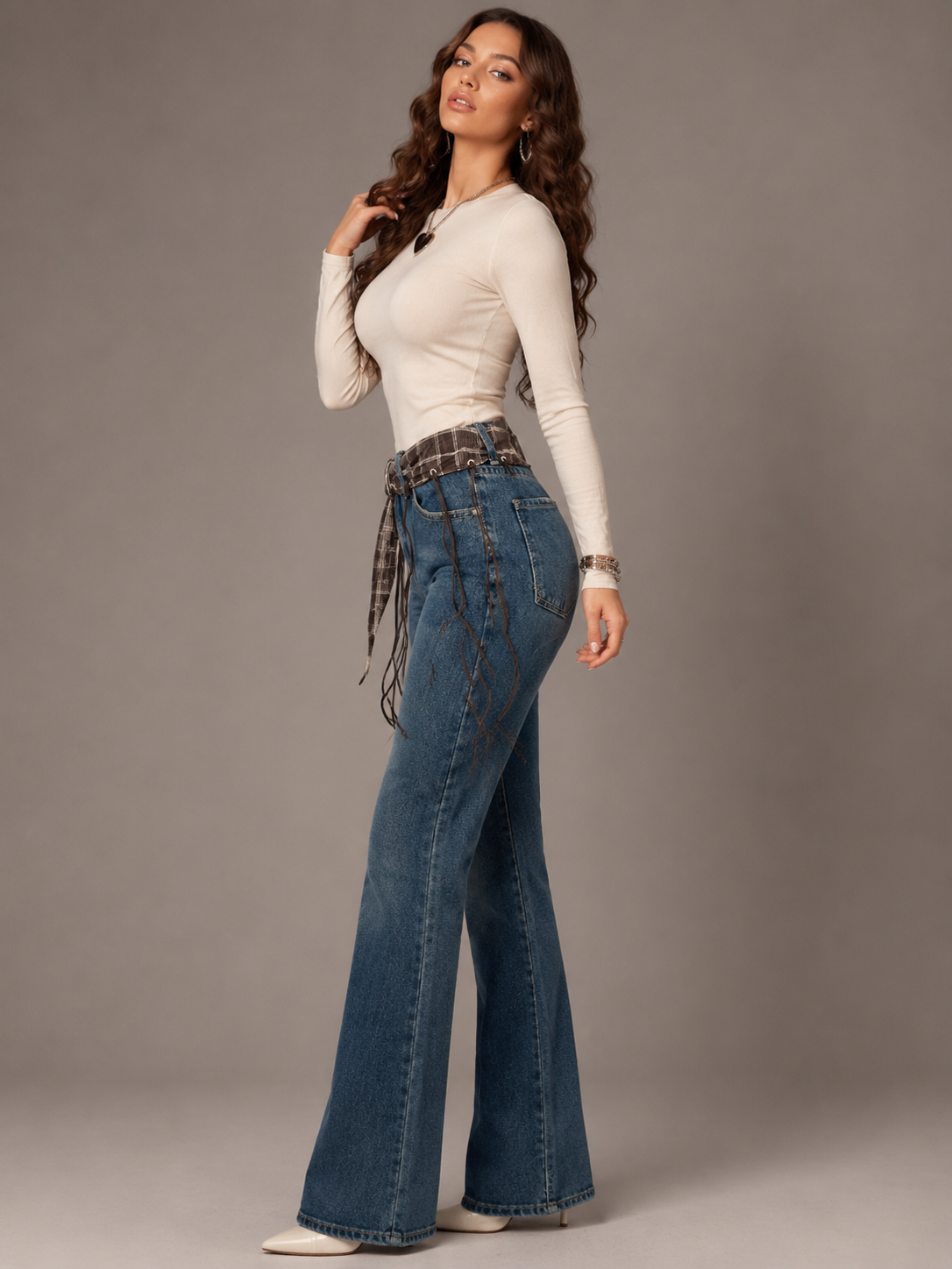 Blue flared jeans with a brown plaid belt featuring fringe.